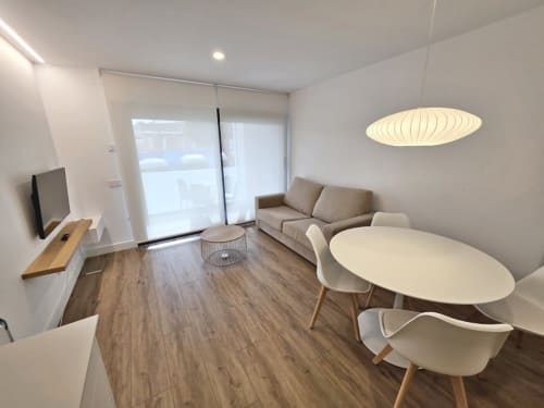 Sala de estar moderna del apartamento BR Silgar Sanxenxo con sofá, mesa de comedor, TV y acceso a terraza