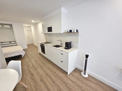 Moderno estudio en BR SILGAR Sanxenxo con cocina blanca, sala, dormitorio y piso de madera