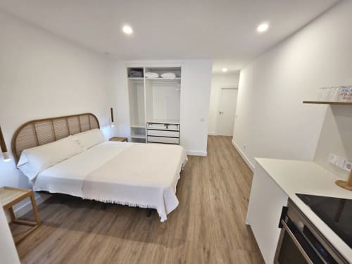 Dormitorio moderno en BR SILGAR Sanxenxo con cama doble, armario empotrado, suelos de madera y zona de cocina