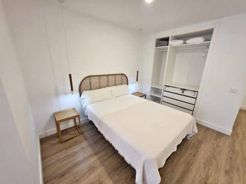 Dormitorio moderno en BR SILGAR Sanxenxo con cama de ratán, armario empotrado, suelo de madera y decoración minimalista blanca