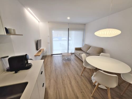 Apartamento moderno en BR SILGAR Sanxenxo con salón abierto, cocina, sofá, mesa comedor, TV y puertas acristaladas a terraza