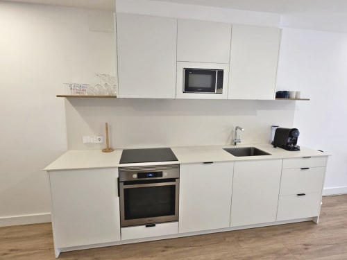 Cocina moderna de diseño blanco con electrodomésticos de acero inoxidable, fregadero y microondas en apartamento BR SILGAR, Sanxenxo