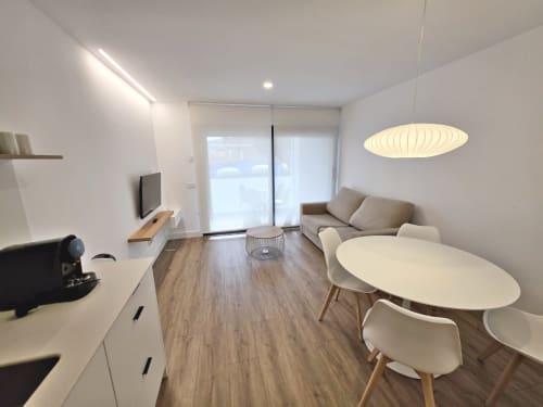 Sala de estar moderna en BR Silgar Sanxenxo con sofá, mesa de comedor, cocineta y acceso a terraza