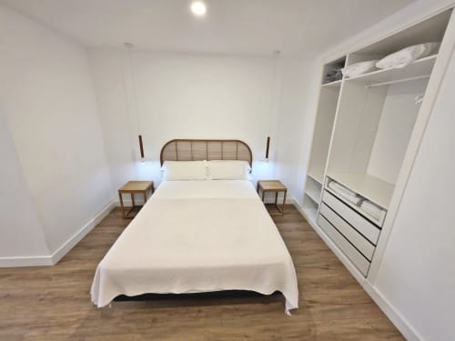 Dormitorio moderno en apartamento BR SILGAR Sanxenxo con cama, mesillas de madera y armario empotrado