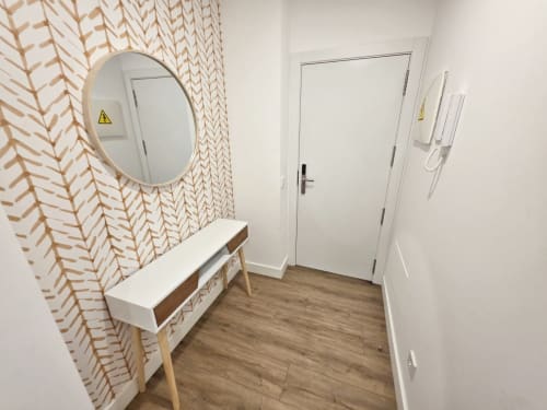 Entrada moderna del apartamento BR Silgar en Sanxenxo con papel pintado estampado, consola de madera, espejo redondo y puertas blancas