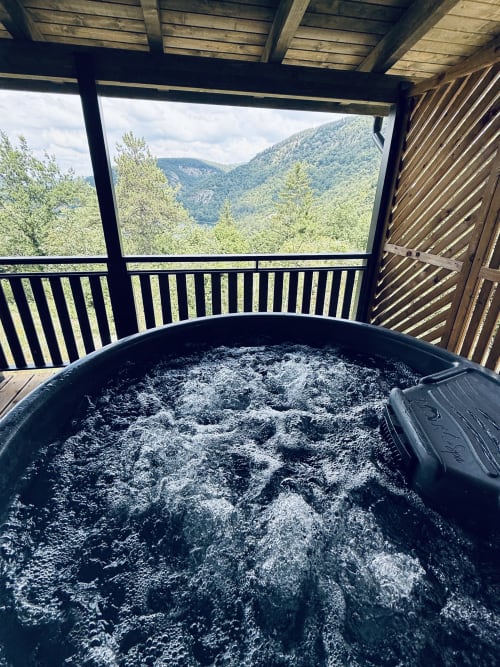 Bain à remous fumant sur la terrasse d'un chalet de montagne surplombant les vallées boisées de Serrières-sur-Ain