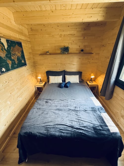 Chambre de lodge en bois confortable avec lit queen-size, lampes de chevet, étagères murales et intérieur chaleureux en pin