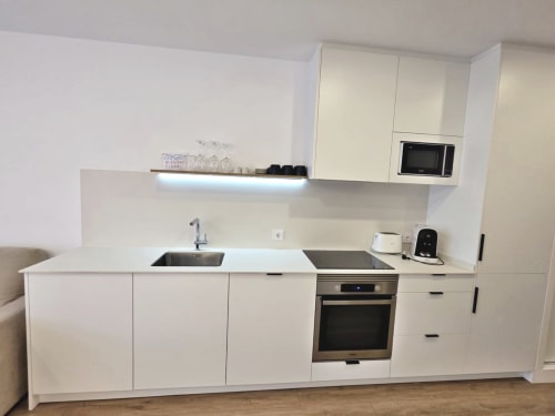 Cocina moderna blanca con electrodomésticos de acero inoxidable en apartamento Sanxenxo Silgar, con fregadero y horno integrado