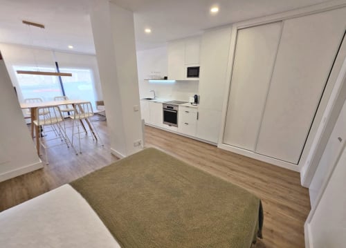 Cocina y sala modernas del hotel BR Silgar en Sanxenxo con muebles blancos y acceso a balcón con vista al océano