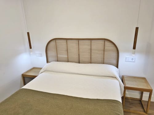 Dormitorio moderno en BR SILGAR Sanxenxo con cabecero de ratán, ropa de cama blanca, mesitas de noche de madera y lámparas colgantes