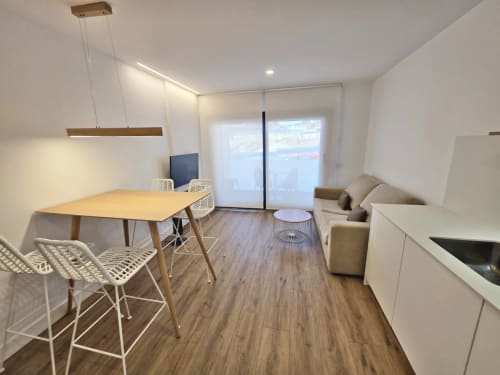 Moderno salón de apartamento en BR Silgar, Sanxenxo con mesa de comedor, sofá, cocina y acceso a terraza