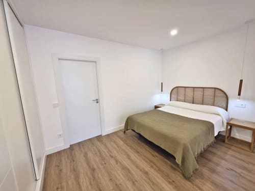 Habitación luminosa en BR Silgar Sanxenxo con cama doble, mesita de noche de madera y piso laminado