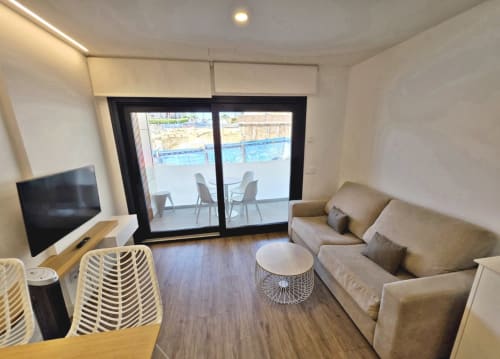 Apartamento BR SILGAR en Sanxenxo con sofá beige, TV y terraza con vistas a la piscina