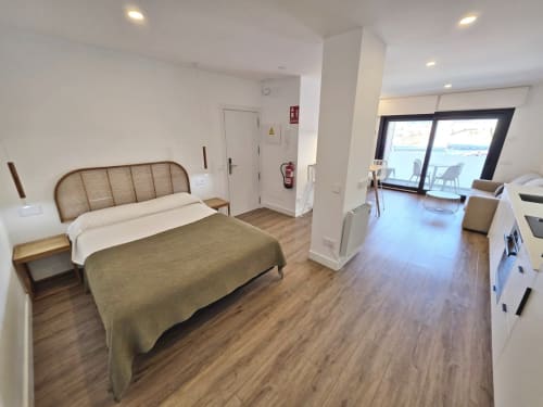 Dormitorio moderno en BR Silgar Sanxenxo con cama de madera, acceso a terraza y comodidades contemporáneas