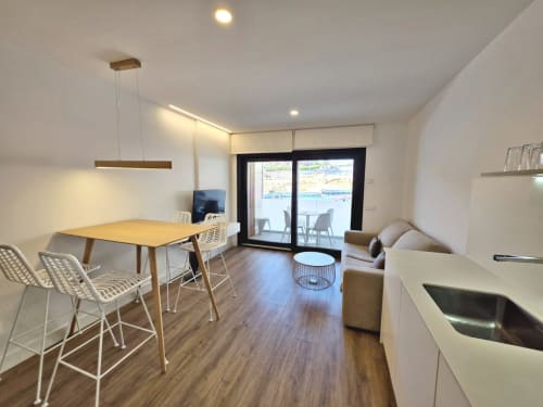 Apartamento moderno en BR SILGAR Sanxenxo con sala abierta, mesa de comedor, sofá, cocina americana y terraza con vistas al mar