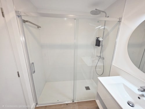 Baño moderno en BR Silgar con ducha tipo walk-in, lavabo blanco y espejo redondo en apartamento de Sanxenxo