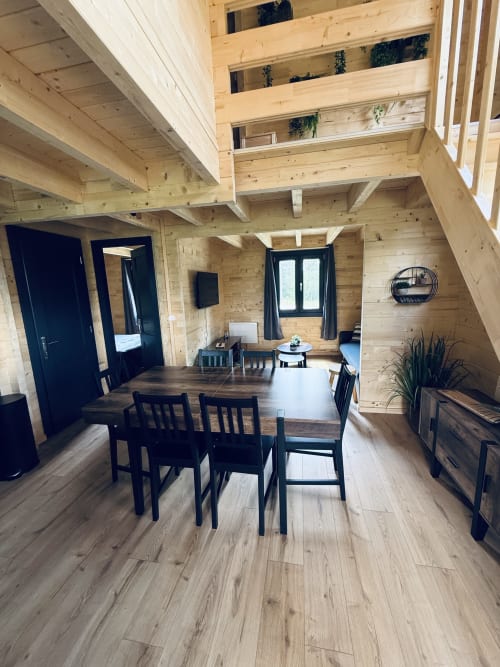 Intérieur de lodge en bois moderne avec table à manger, chaises noires et espace de vie ouvert aux Cabanes et lodges du Belvédère
