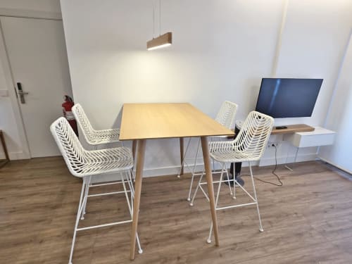 Comedor moderno en apartamento de Sanxenxo con mesa de madera, sillas tejidas blancas, televisión e iluminación colgante