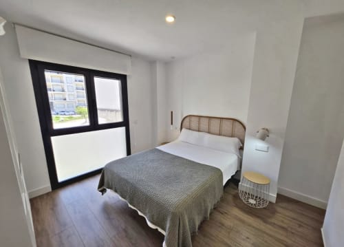 Habitación moderna en el hotel BR Silgar de Sanxenxo con cama, balcón, suelos de madera y mobiliario contemporáneo
