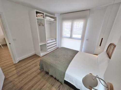 Dormitorio moderno y luminoso en BR SILGAR Sanxenxo con cama, armario empotrado y acceso a balcón
