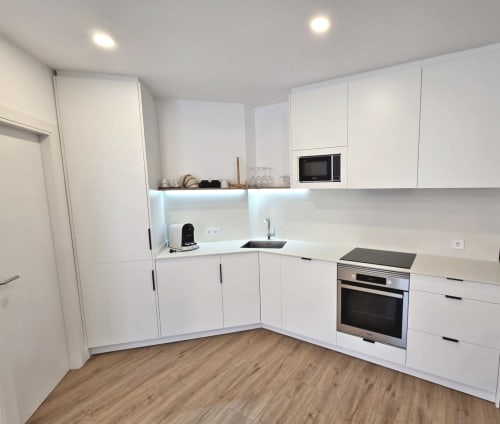Cocina moderna blanca con horno y microondas integrados en el apartamento BR Silgar de Sanxenxo