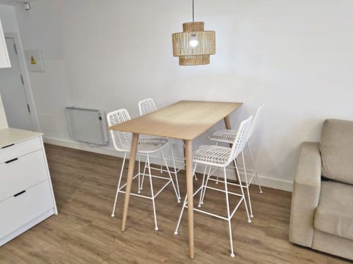 Comedor moderno en apartamento de Sanxenxo con mesa de madera, taburetes blancos y lámpara colgante contemporánea