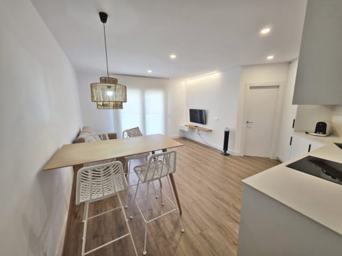 Cocina y comedor del apartamento moderno Sanxenxo con mesa de madera, barra y acceso a la sala en el hotel BR SILGAR
