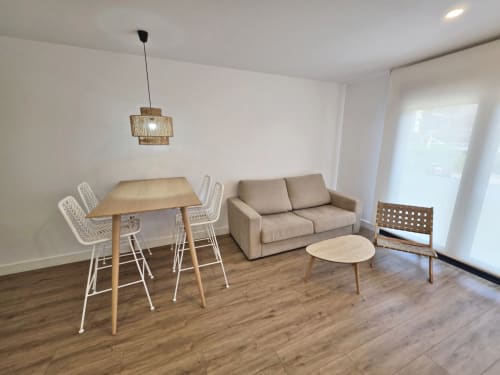 Moderna sala de estar en BR Silgar Sanxenxo con sofá, mesa de comedor, lámpara colgante y pisos de madera