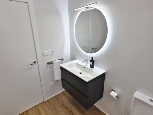 Baño moderno en apartamento BR Silgar Club 2, Sanxenxo con espejo redondo iluminado y vanidor negro
