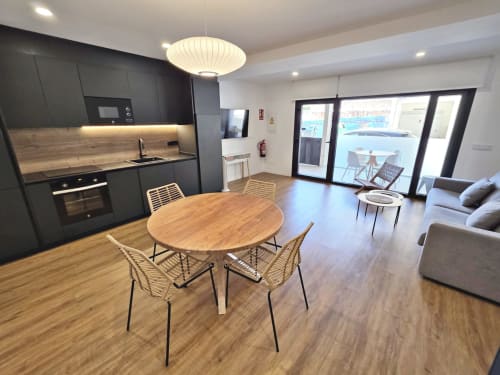 Apartamento BR Silgar Club 2 en Sanxenxo: vivienda moderna diáfana con cocina negra, mesa de madera y vistas a la terraza
