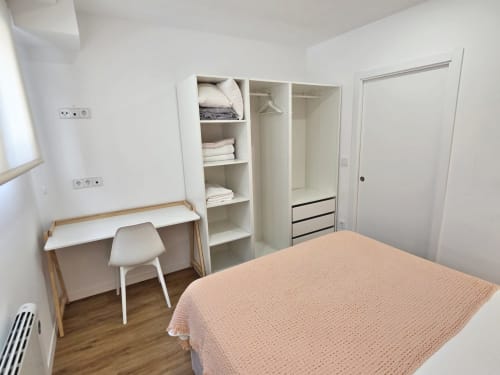 Dormitorio moderno en BR Silgar Club 2 de Sanxenxo con cama, escritorio, silla, armarios empotrados y estanterías de almacenamiento