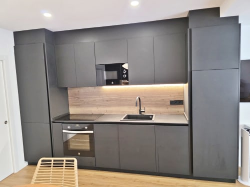 Cocina moderna gris con revestimiento de madera y encimeras negras en apartamento BR Silgar Club 2, Sanxenxo