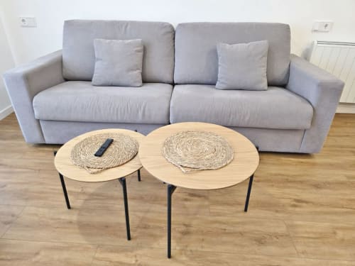 Sofá gris con cojines decorativos y dos mesitas laterales redondas de madera en la sala de estar del apartamento BR Silgar Club 2