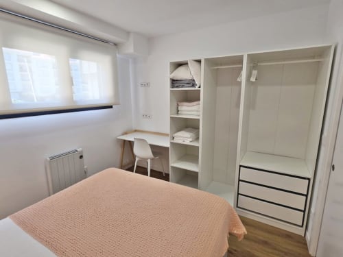 Habitación moderna en BR Silgar Club en Sanxenxo con cama, escritorio, armarios empotrados blancos y estanterías