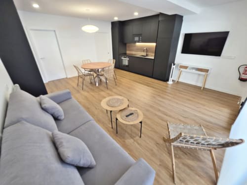 Apartamento BR Silgar Club en Sanxenxo con sala de estar diáfana moderna, cocina negra, comedor, sofá gris y suelos de madera