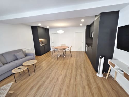 Apartamento BR Silgar Club 2 en Sanxenxo con sala de estar moderna de planta abierta, suelos de madera, mesa de comedor, sofá gris y negro