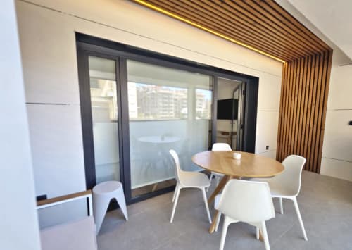 Comedor del apartamento BR Silgar Club 2 con mesa de madera, sillas blancas y balcón con vistas a Sanxenxo