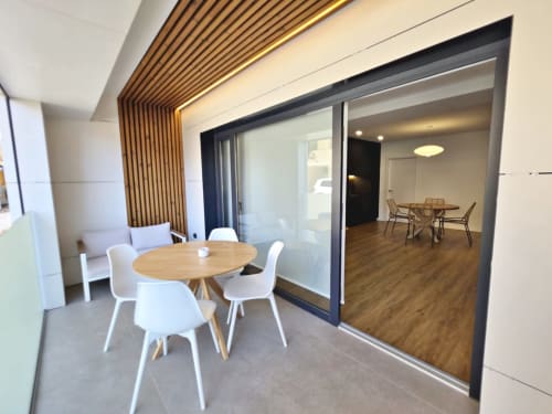 Apartamento BR Silgar Club en Sanxenxo con comedor, mesa redonda, sillas blancas y puertas correderas de vidrio hacia el salón