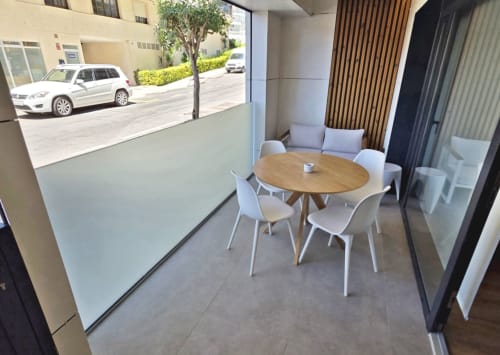 Elegante comedor en el apartamento BR Silgar Club de Sanxenxo con mesa redonda de madera, sillas blancas y vistas a la calle