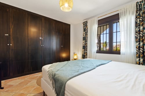 Bright bedroom at Ayma Casa Nísperos in Alhaurín de la Torre with dark wood wardrobes, terracotta floors, and pool views