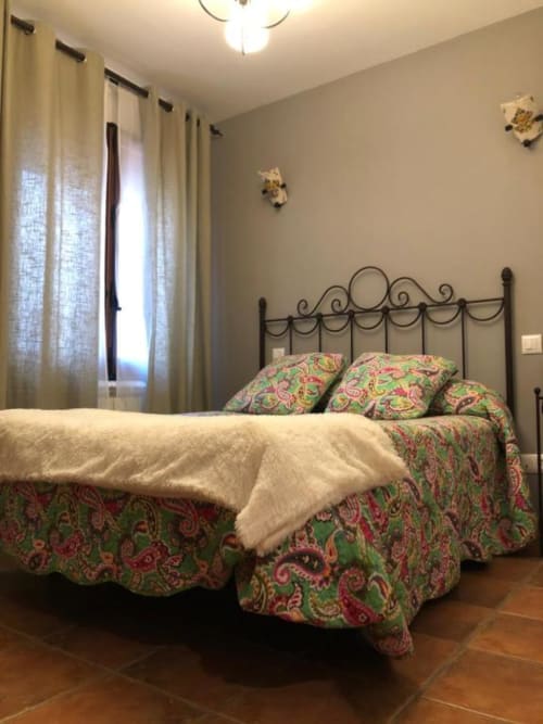 Elegante dormitorio doble en Casa Rural El Infante, Oropesa con cama de hierro forjado y ropa de cama con estampado paisley colorido