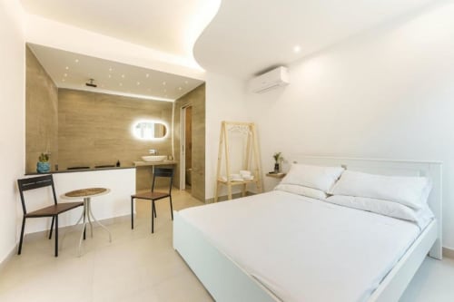 Camera moderna dell'hotel Il Poeta a Procida con letto bianco, bagno en-suite, zona studio e arredi contemporanei