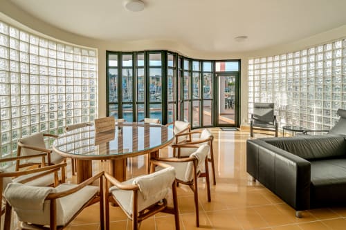 Vila moderna com sala de estar e vista para o mar, mesa de jantar redonda, cadeiras mid-century, paredes de blocos de vidro, acesso ao terraço em Albufeira