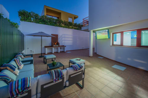 Terraço na cobertura da Villa Odyssey em Albufeira com espreguiçadeiras, zona de refeições e vista para o mar ao entardecer