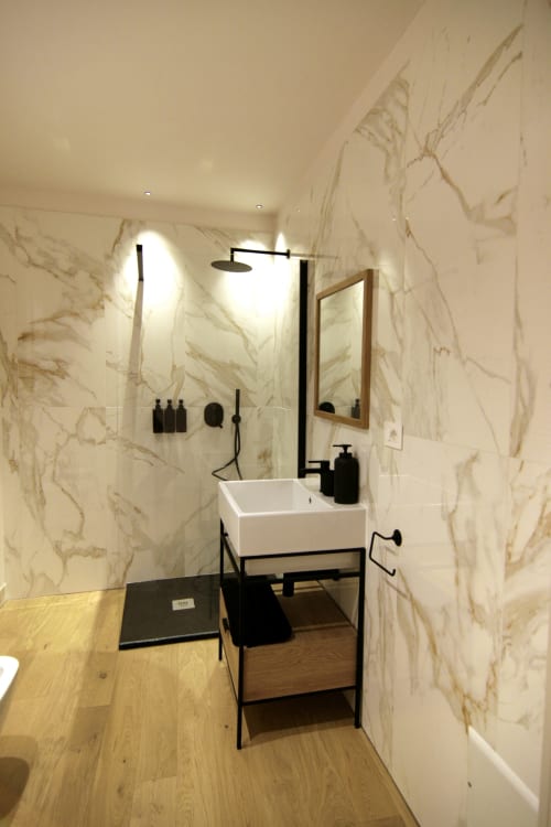 Bagno moderno a Residenza Basiglio con pareti in marmo, lavabo bianco, rubinetteria nera e doccia aperta a Ceva, Italia