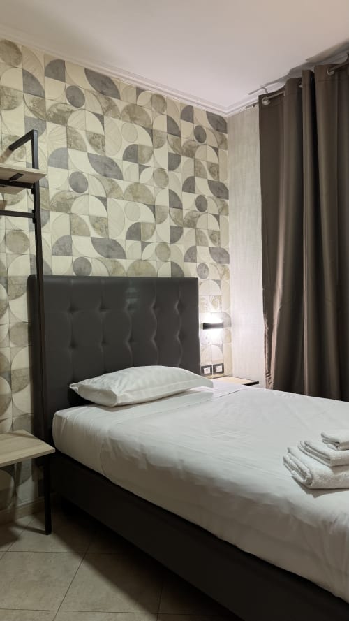 San Paolo Guest House single room in Rome with black bed, geometric patterned accent wall, and modern amenities