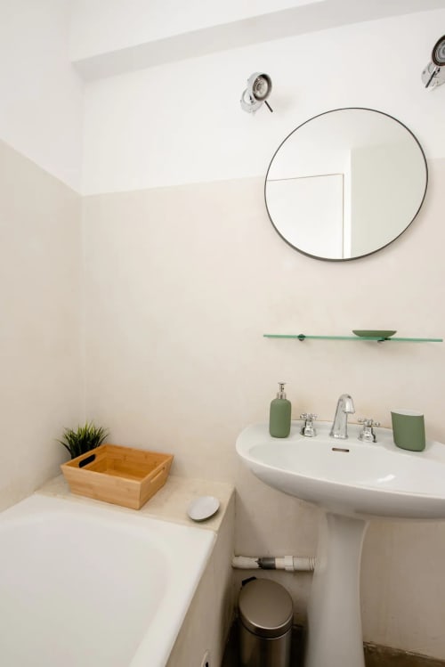 Salle de bains moderne à YOU CAMP IMMOBILIER avec miroir circulaire, lavabo sur piédestal et touches de vert
