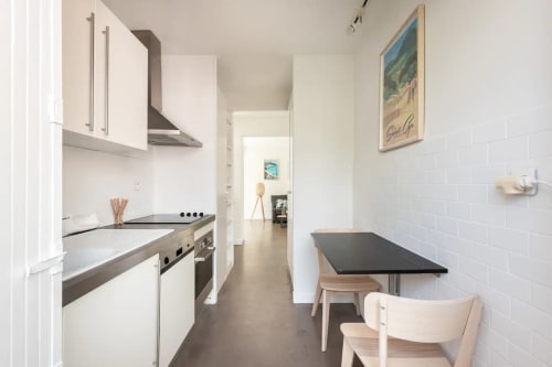 Cuisine blanche moderne avec coin repas, électroménagers en acier inoxydable et vue mer à Saint-Cyr-sur-Mer