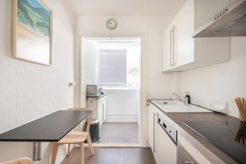 Cuisine moderne à Saint-Cyr-sur-Mer avec placards blancs, plan de travail foncé et salle à manger vue mer