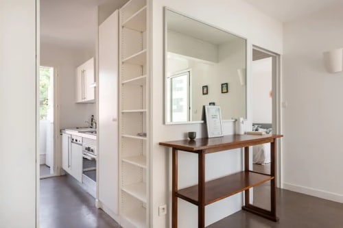 Intérieur moderne d'appartement avec console en bois, étagères blanches et cuisine à Saint-Cyr-sur-Mer